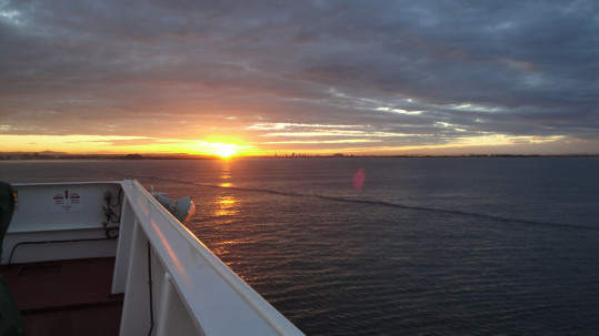 Sun rising over an Ofer Global ship